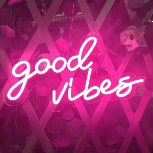 We zien een roze neon muurlamp met de woorden good vibes verlicht.
