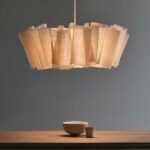 Geplooide stoffen hanglamp in Japanse stijl boven een houten tafel