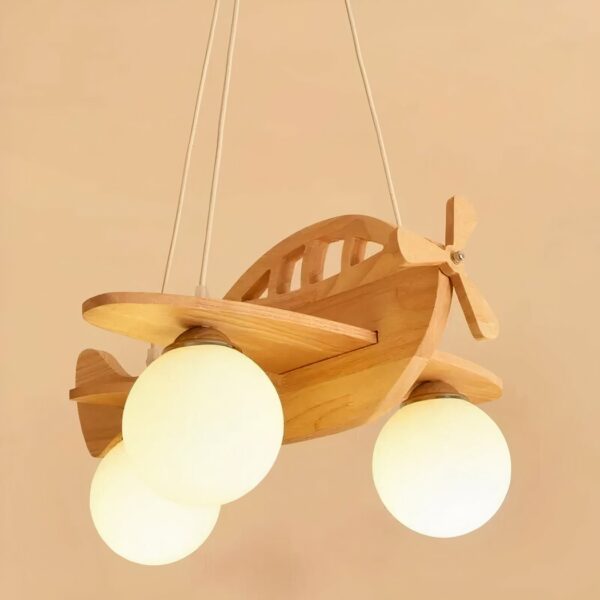 Houten hanglamp in de vorm van een vliegtuig, met 3 witte bollen voor de lampen. Hangt met 3 draden aan een houten voet die aan het plafond hangt. Beige achtergrond.
