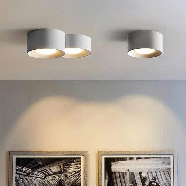 Moderne LED kroonluchter in een minimalistisch cilinderontwerp en inbouwspot in wit, bevestigd aan het plafond en verlicht, in een woonkamer.