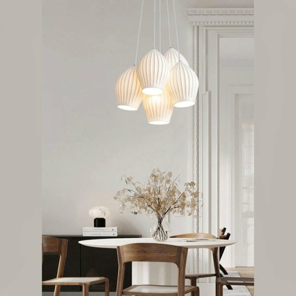 Hanglamp met vijf witte keramische kappen boven een eetkamertafel versierd met een bonsaiboom op een grijze achtergrond.