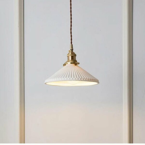 een vintage-stijl ophanging van wit keramiek en koper is te zien tegen een witte achtergrond