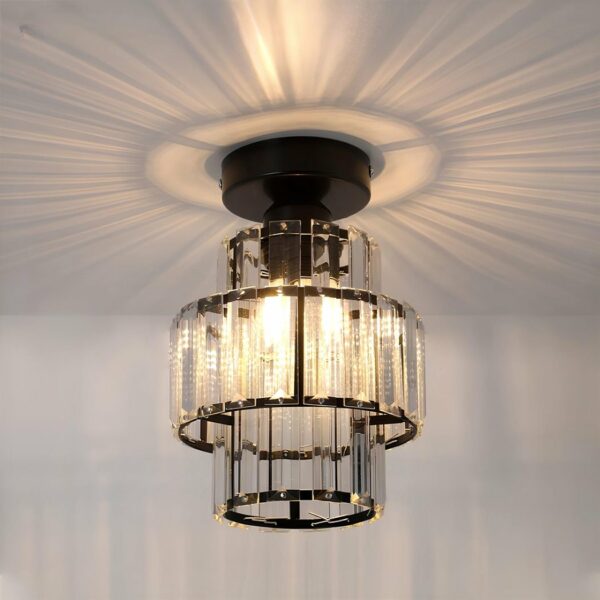 Cilindrische plafondlamp met 3 rijen lamellen in kristalstijl. De plafondsteun is zwart en de lamellen zijn op zwarte cirkels gemonteerd. De lampen branden en stralen op het plafond rond de kroonluchter.