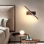 Draaibare LED-wandlamp met warm licht boven een nachtkastje